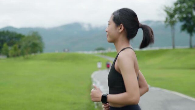 Female runner warming up by jogging in place at an outdoor park, representing fitness preparation, healthy lifestyle, cardio exercise, wellness and longevity concept.