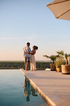 Romantic couple enjoying in sunset by the pool during summer vacation.