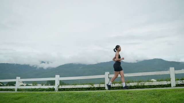 Woman walking uphill on an outdoor path while holding a water bottle, representing exercise, hydration, healthy lifestyle, wellness and longevity concept.