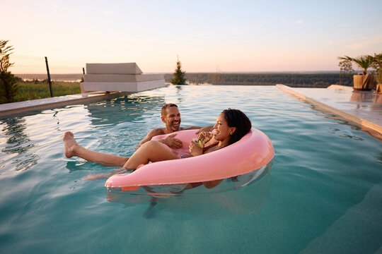 Happy couple having fun in infinity pool during summer holiday.