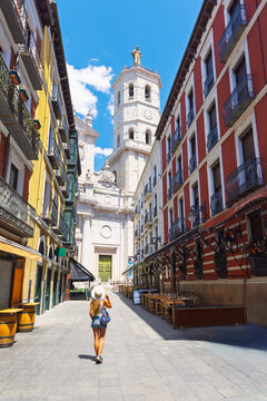 Woman tourist walking through narrow historic street in Valladolid, Spain towards the landmark Cathedral