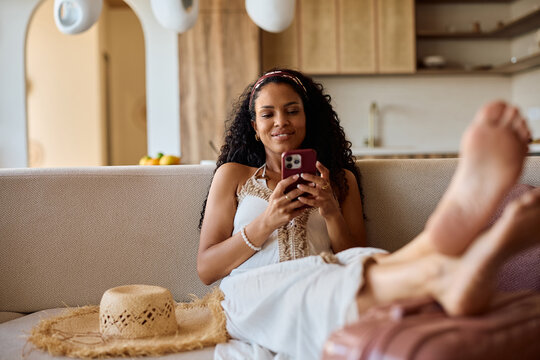 Relaxed black woman using smart phone after arriving into a hotel on summer vacation.