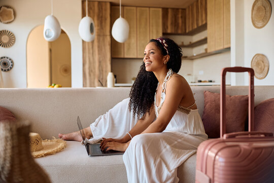 Happy black woman using laptop while making a reservation for summer holiday.