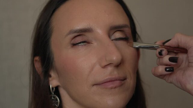 Makeup application woman face applying concealer under eye with a brush
