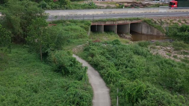 Smooth aerial drone footage of a highway with a car and truck traveling through a green rural landscape. Ideal transportation, infrastructure and travel concept with countryside scenery and modern roa
