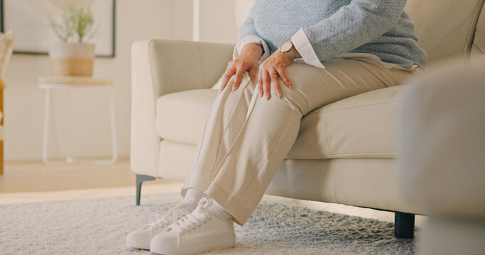 Hands, old person or knee pain in home, injury and arthritis with muscle tension in living room. Sore legs, retirement or woman on sofa with gout, osteoporosis or tendinitis from health problem