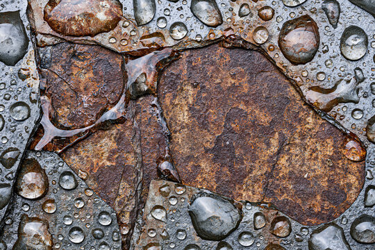 Top view of clear raindrops on wet rusty stone texture