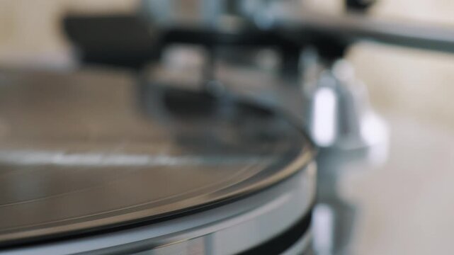 Carbon fiber brush cleaning vinyl record before playback, removing dust from LP surface on turntable, closeup of analog audio maintenance.