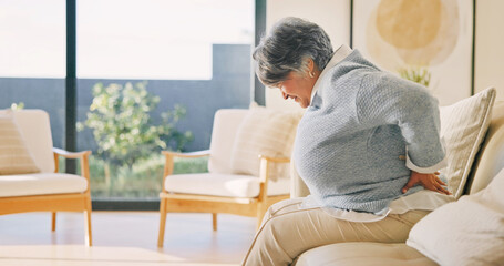 Fototapeta premium Elderly, woman or back pain on sofa, injury or fibromyalgia with osteoporosis in living room. Discomfort, retirement or person with sore spine at home, arthritis or muscle tension with health problem