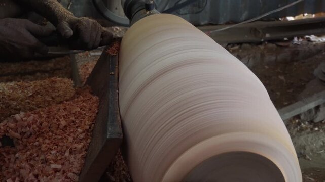 Woodworker Shaping Cylindrical Timber on Lathe