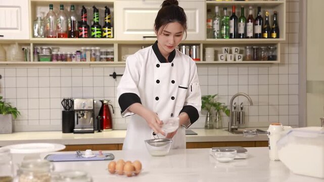 Pastry chef baker sift flour through a metal sieve into mixing white glass bowl to aerate for sponge cake batter, preparing dough for baking preparation recipes, food blogs in modern kitchen