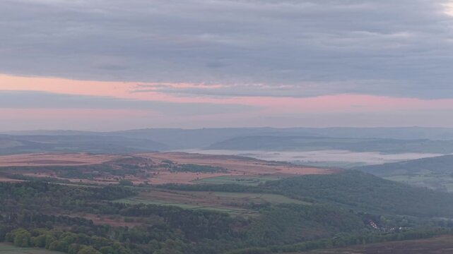 Slow drone pan from right to left from Higger Tor looking towards the Burbage Valley at sunrise in the summer