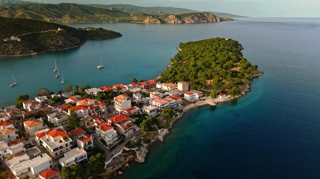Aerial panorama of Ermioni peninsula featuring charming Greek architecture, dense pine woodland, and crystal-clear Mediterranean waters