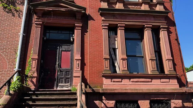 Low-angle shot of a sunlit, abandoned brownstone building in Brooklyn.