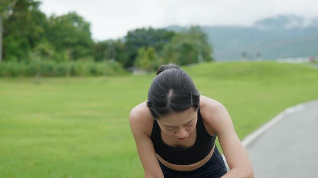Tired woman checking her smartwatch after running outdoors in a park, showing fitness tracking, recovery, healthy lifestyle and personal wellness.
