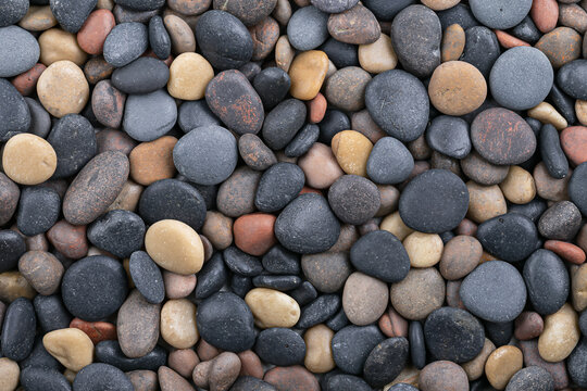 Overhead view of mixed colorful river pebbles smooth stones texture