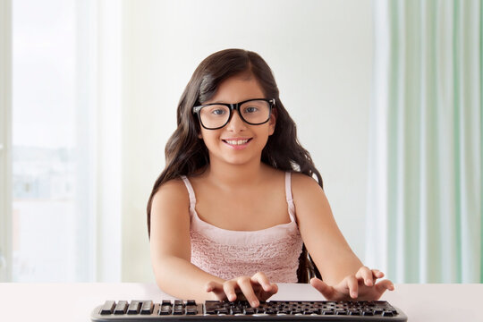Girl with big black glasses typing on keyboard