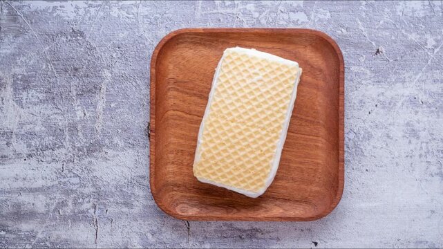 Timelapse: dissolution of waffles ice cream on wooden square plate, top view	