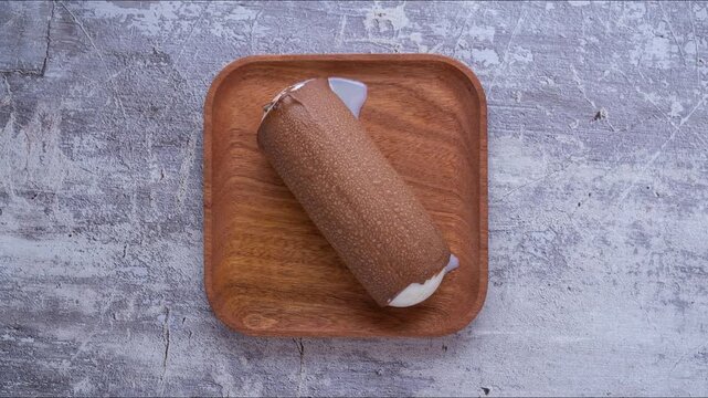 Timelapse: dissolution of ice cream on wooden square plate, top view	