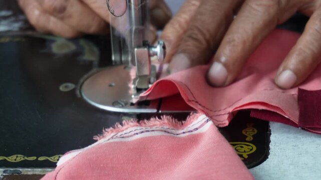 Hands Sewing Pink and Maroon Fabric on Machine