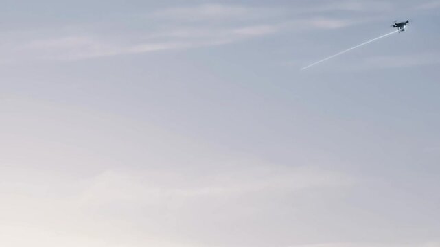 A plane flies through the sky leaving a trail of condensed water vapor.