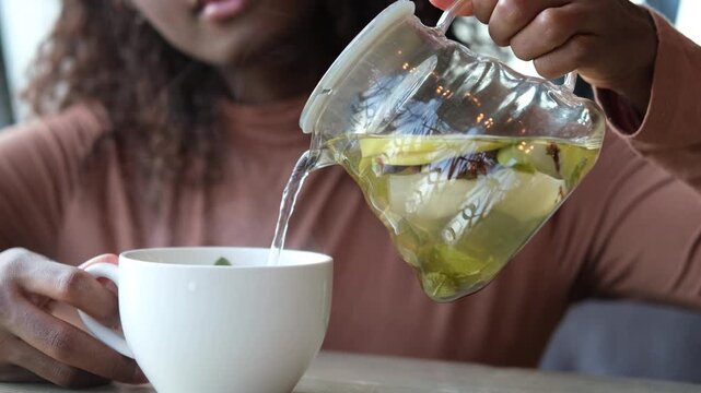 Female hands pour hot fruit tea into a cup in the morning during the cold season