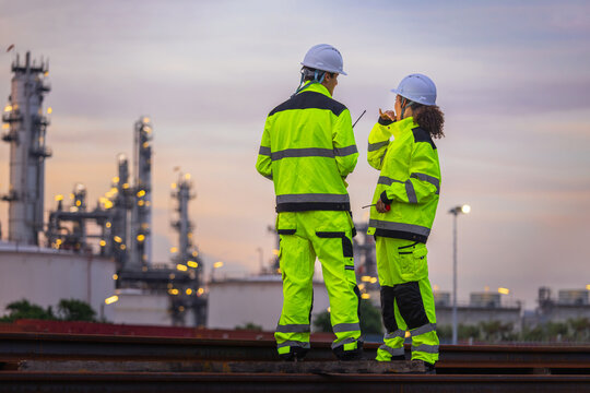 Industrial engineers team discussing project work at oil refinery at sunset, Site managers in high-visibility clothing inspecting at a petrochemical plant