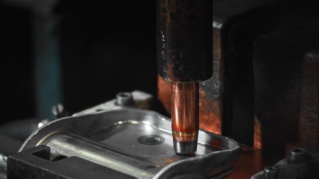 Copper electrode contacting stamped steel automotive housing during spot welding inside industrial workshop with precise alignment over fastener hole and visible heat tint