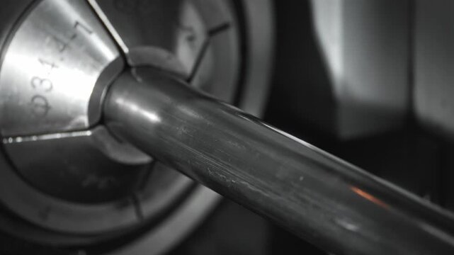 Automatic laser cutting stainless steel pipe, orange sparks streaming from precision nozzle inside CNC machine during industrial fabrication and metalworking process