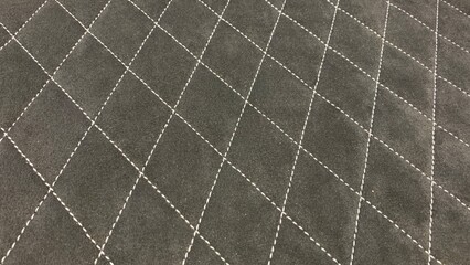 Fototapeta premium Black quilted fabric surface featuring diamond stitching pattern, suitable for upholstery, automotive, and decorative applications