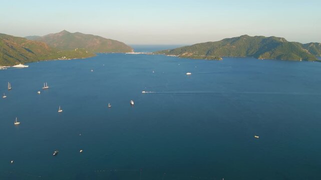 Marmaris, Turkey. Marmaris Bay, a deeply indented natural harbor enclosed by pine-covered peninsulas and forested mountains, aerial view at golden hour with scattered yachts and warm sunset light. Ae