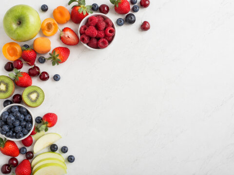Muestra variada de frutas frescas en un fondo claro con diferentes tipos de bayas y frutas de color brillante