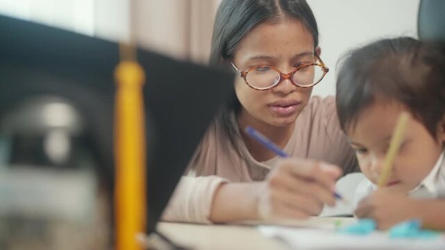 Asian Mother Supporting Young Daughter with Homework and Early Education at Home
