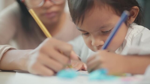 Asian Mother Helping Young Daughter Practice Writing and Learning Together at Home