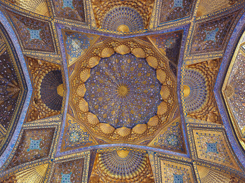 Gilded dome interior of Ak Saray Mausoleum in Samarkand with intricate muqarnas and blue tilework. Stunning example of Timurid architecture ideal for travel and cultural heritage publications.