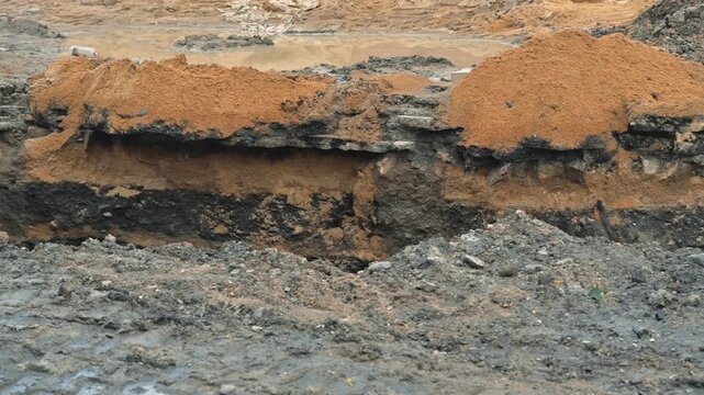 process of soil removal at a construction site. Heavy machinery is used to dig deep into the earth while piles of excavated dirt accumulate nearby