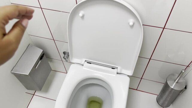 Close view of an open toilet seat and lid in a clean tiled bathroom, showing a simple restroom interior from above with white fixtures and a practical everyday setting.