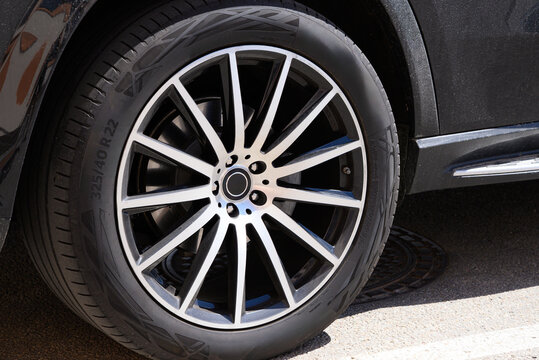 A close-up of a vehicle's wheel featuring a multi-spoke alloy rim and a tire with the specifications 325/40 R22. The wheel is part of a black car parked on a street, with the smooth texture of the tir