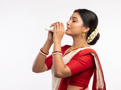 Beautiful Bengali Woman with Eyes Closed Blowing Traditional Shankha During Durga Puja Isolated on White Background