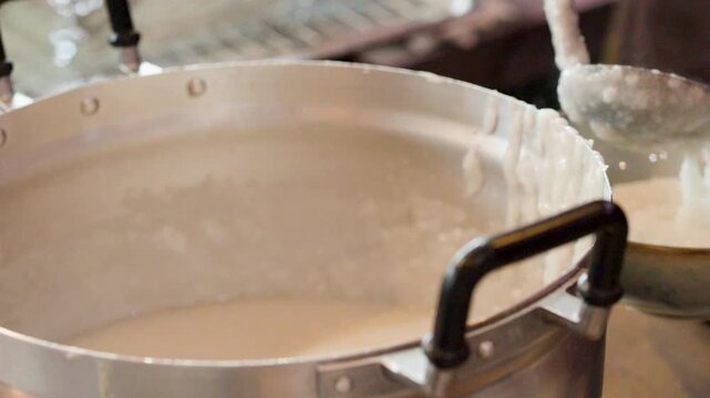 Chef Serving Hot Asian Rice Porridge Into Bowl From Large Pot