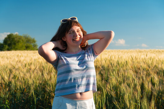 Happy young woman enjoying summer breeze in wheat field