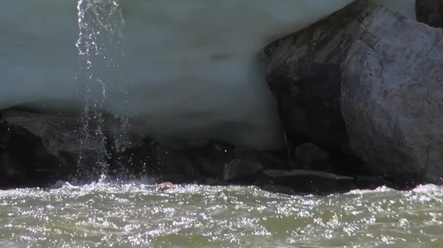 Mesmerizing cascade of pure water pours from icy ledge, meeting vibrant currents of Lake Khuvsgul, Mongolia. Glistening sunlight dances on pristine surface, true spectacle of nature's beauty.