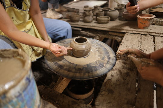 Artisan Shaping Clay Pot on Spinning Pottery Wheel in Workshop