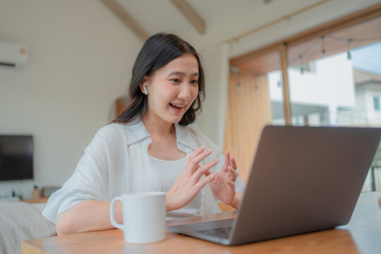 Young Asian tutor explaining topic with both hands during virtual class on computer, enthusiastic online teacher working from home.