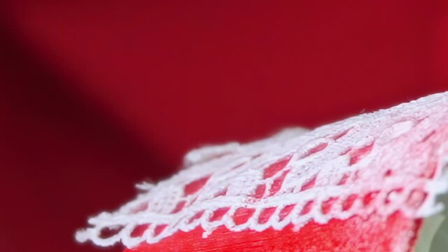 Close focus on sumptuous scarlet material, delicately enhanced by ornate white lace. The gentle curves and soft textures intertwine, presenting a graceful, artistic textile composition.