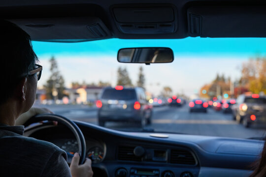 Driver navigating through urban traffic, keeping safe following distance. Red brake lights from vehicles ahead. California. USA.