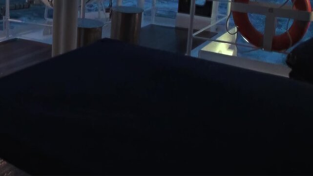 A captivating glimpse from a ship navigating the vast Arctic Ocean at twilight. Rippling dark waters reflect the dim light, bordered by the ship's sturdy railing and a vibrant life preserver.