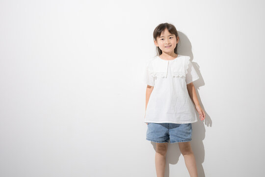 白背景の前で立つ笑顔の日本人の女の子　全身ポートレートとコピースペース