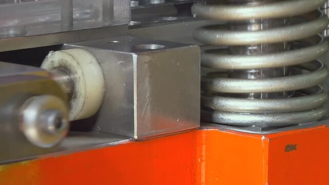 Close-up view of a powerful industrial machine in action. The device presses metal sheet components, showcasing slow motion movement and intricate details of the process in an industrial setting.