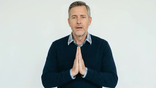 A middle-aged man puts his hands together and bows deeply, looking apologetic.